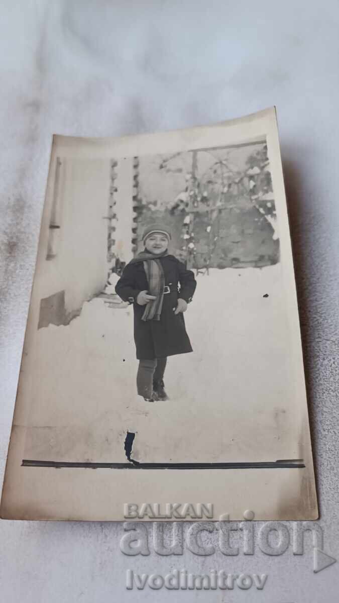 Photo of a little boy in the yard of the house in winter