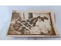 Photo of a little girl in a retro baby carriage in front of a pile of watermelons