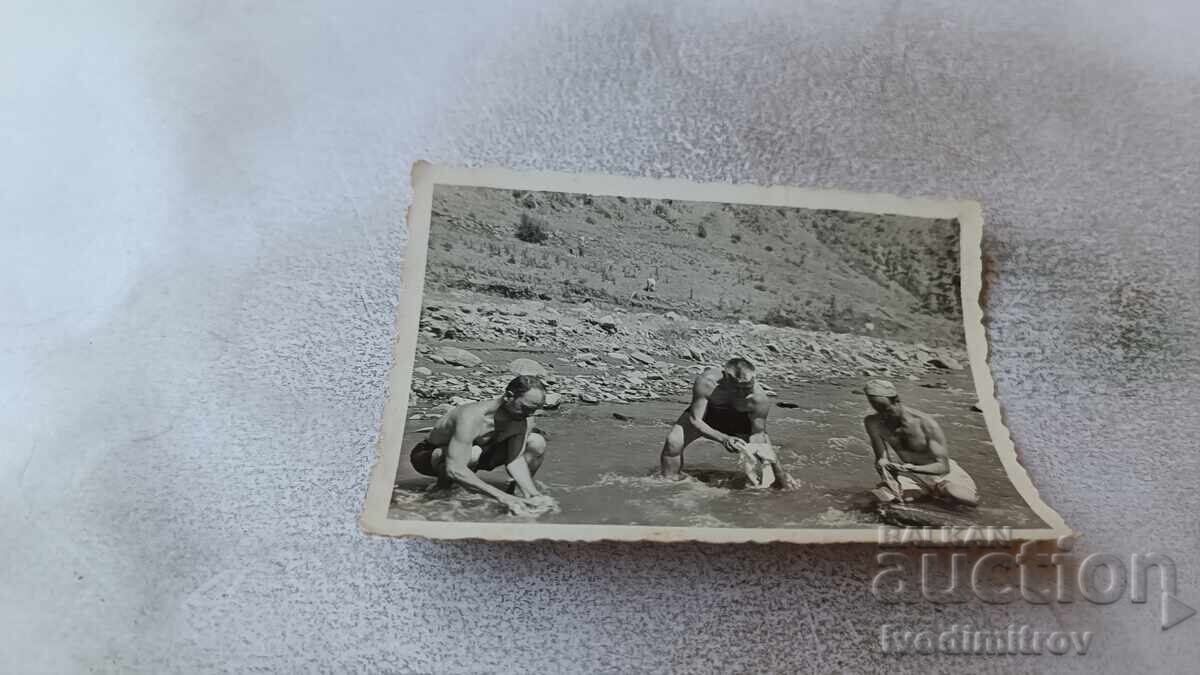 Φωτογραφία Τριών ανδρών που πλένουν ρούχα στο ποτάμι