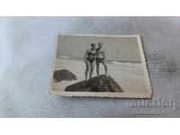 Fotografie cu un bărbat și o femeie pe o stâncă lângă mare