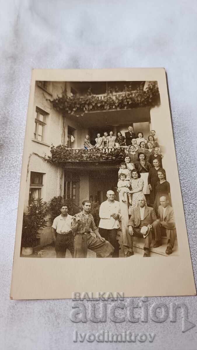 Φωτογραφία Ανδρών, Γυναικών και Παιδιών μπροστά από τριώροφη οικοδομή