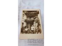 Φωτογραφία Ανδρών, Γυναικών και Παιδιών μπροστά από τριώροφη οικοδομή