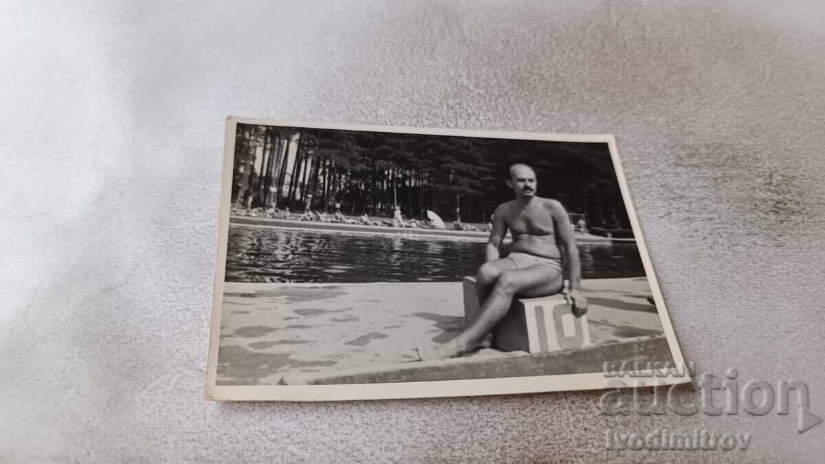 Photo: Man sitting at number 10 of a swimming pool Photo: Man sitting at number 10 of a swimming pool