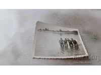 Photo of four young people in retro swimsuits in the sea