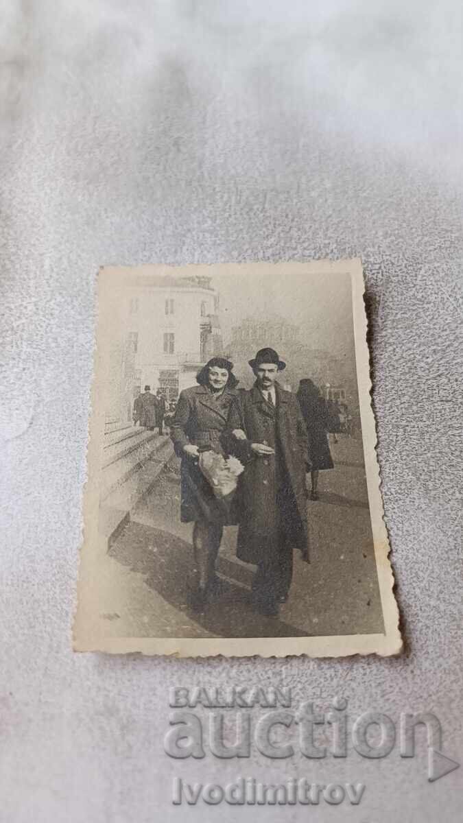 Photo Sofia Man and woman with bouquet in front of the Adjacent Palace Photo Sofia Man and woman with bouquet in front of the Adjacent Palace
