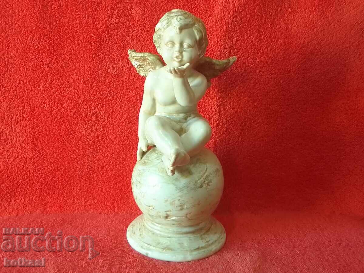 Old porcelain figure of an Angel sitting on a ball