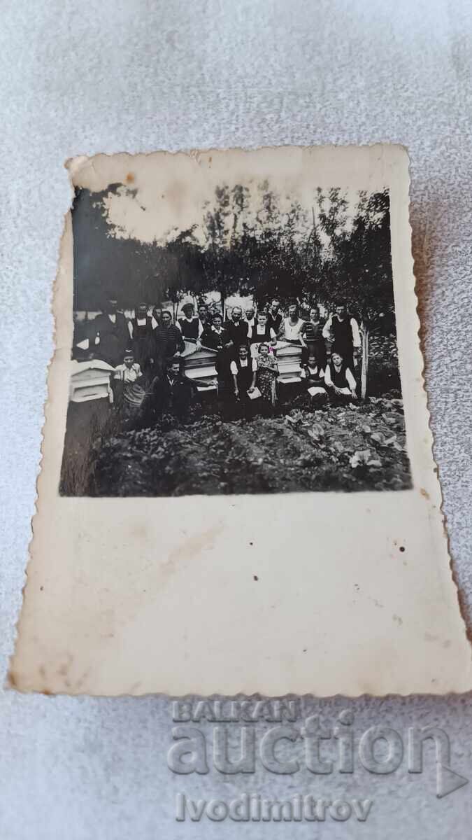 Photograph Men and women near beehives