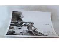 Φωτογραφία Άνδρας κάθεται σε βράχο δίπλα στη θάλασσα