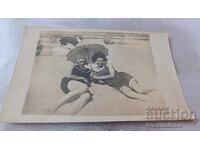 Φωτογραφία Δύο νεαρών κοριτσιών με ρετρό μαγιό και ομπρέλα στην παραλία