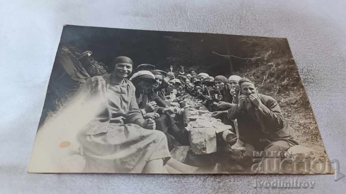 Φωτογραφία Μαδεζών και κοριτσιών που κάθονται σε μακρύ τραπέζι στο δάσος