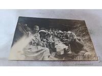 Photo of young men and women sitting at a long table in the forest