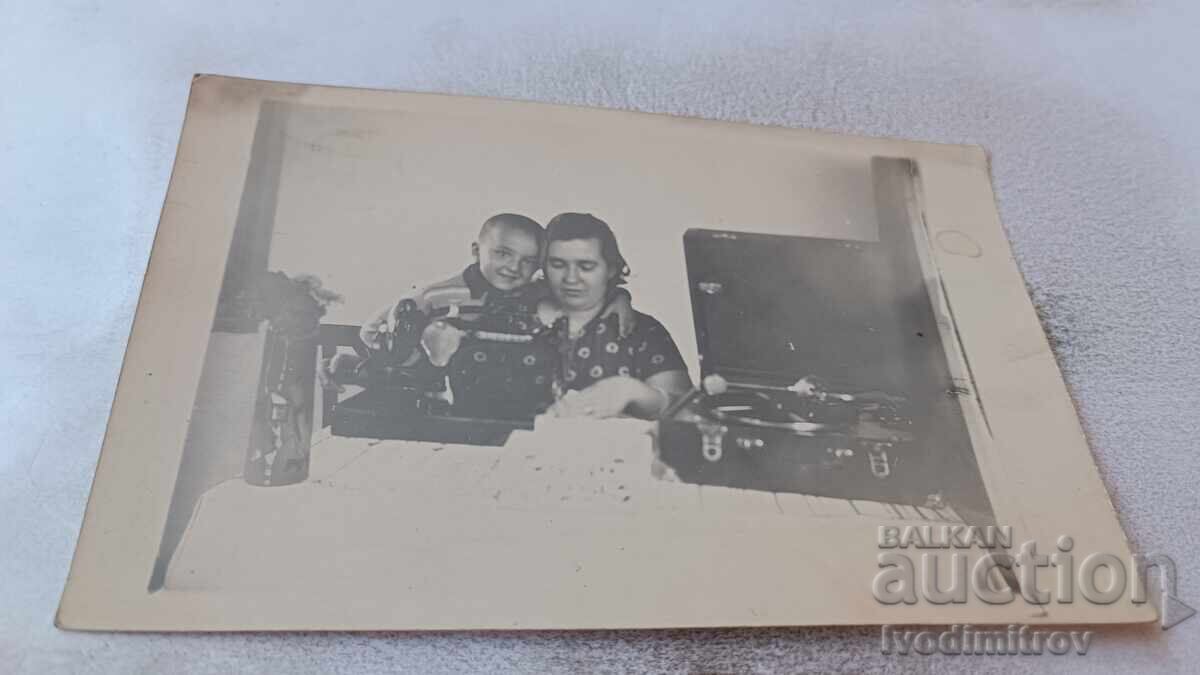 Photo of a Woman and Boy with a Retro Gramophone and Sewing Machine on a Table Photo of a Woman and Boy with a Retro Gramophone and Sewing Machine on a Table