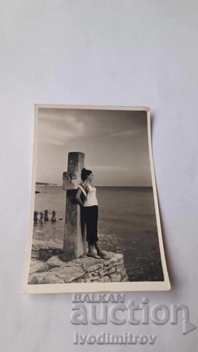 Снимка Младо момиче облегнато на кръст над плажа