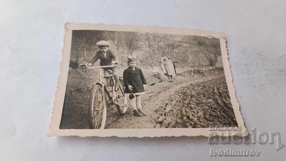 Photo of a girl and a boy with a retro bicycle on the road