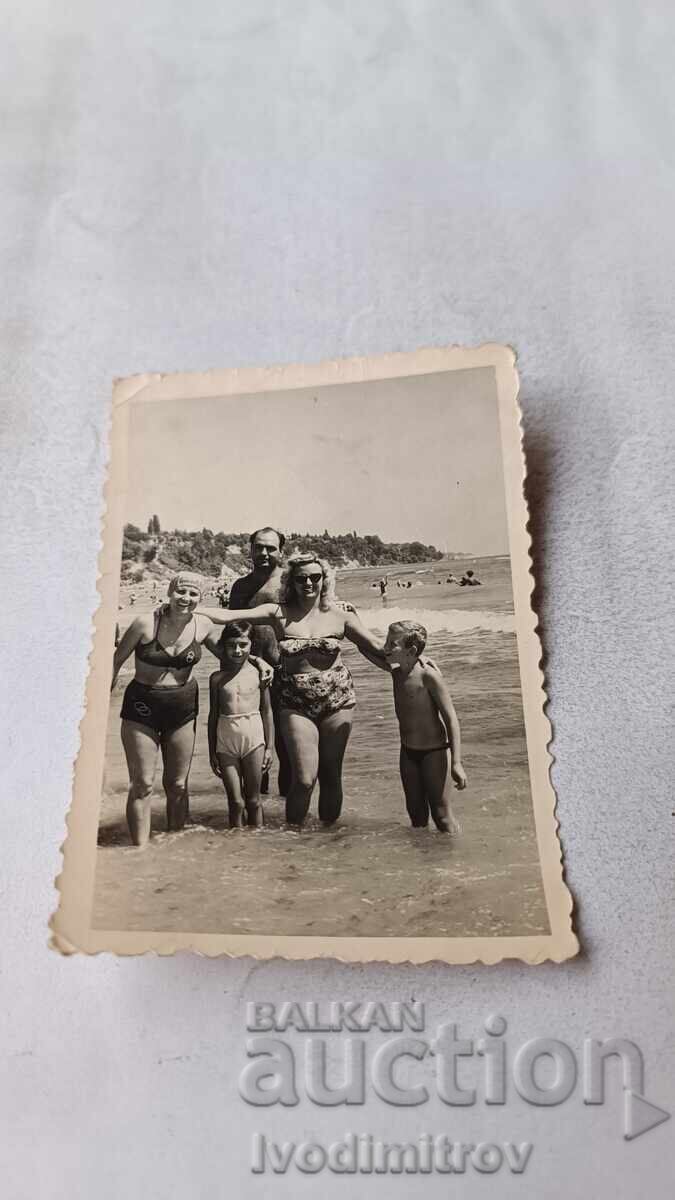 Fotografie bărbat, două femei și doi copii pe malul mării