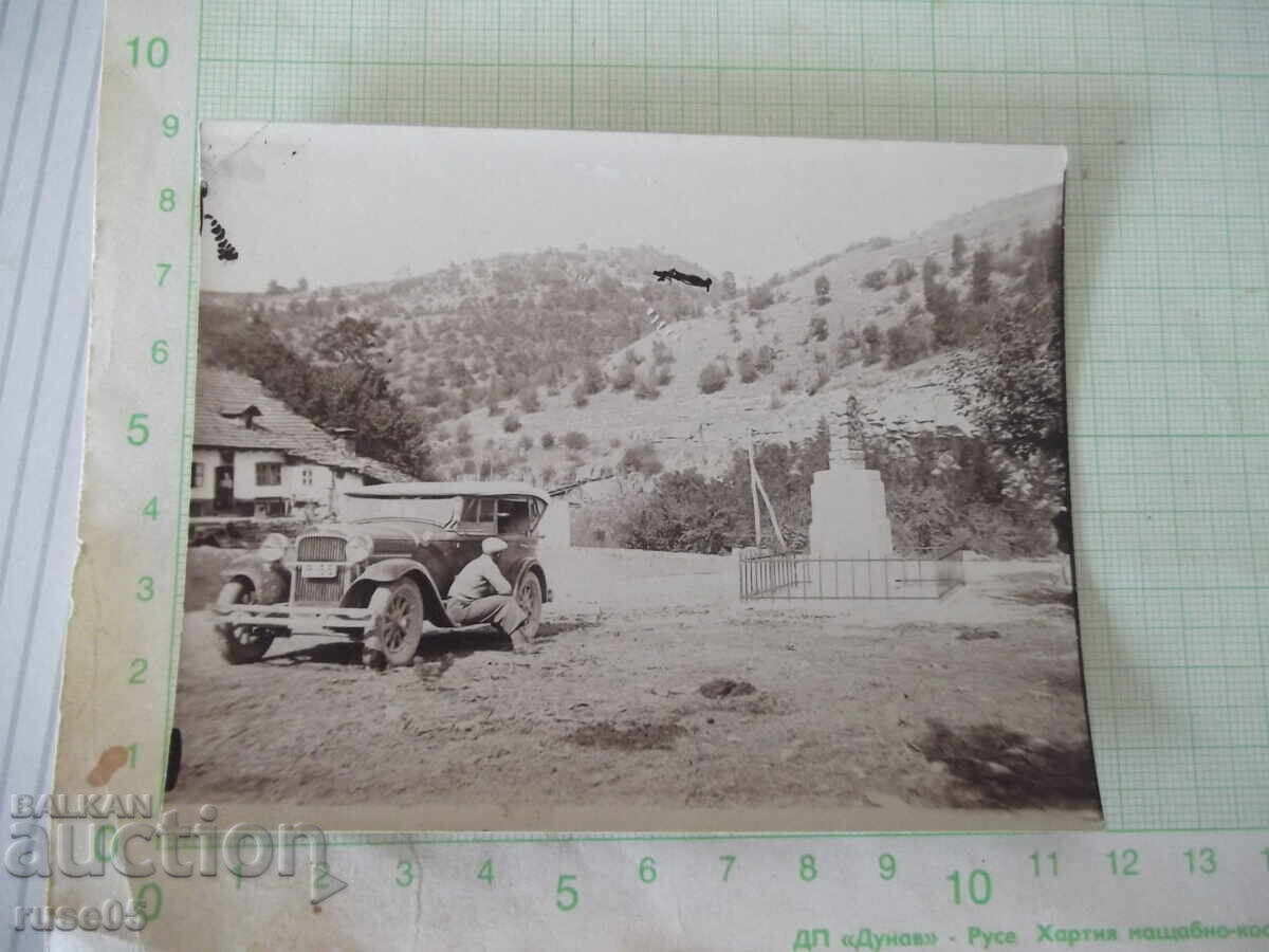 Φωτογραφία οδηγού καθισμένου στο κατώφλι ενός αυτοκινήτου δίπλα σε ένα παλιό μνημείο