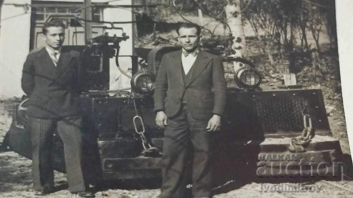 Livrarea Fotografie Doi bărbați în fața unui atelier Livrarea Fotografie Doi bărbați în fața unui atelier