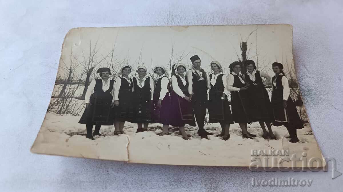 Fotografie bărbat și tinere în haine tradiționale iarna