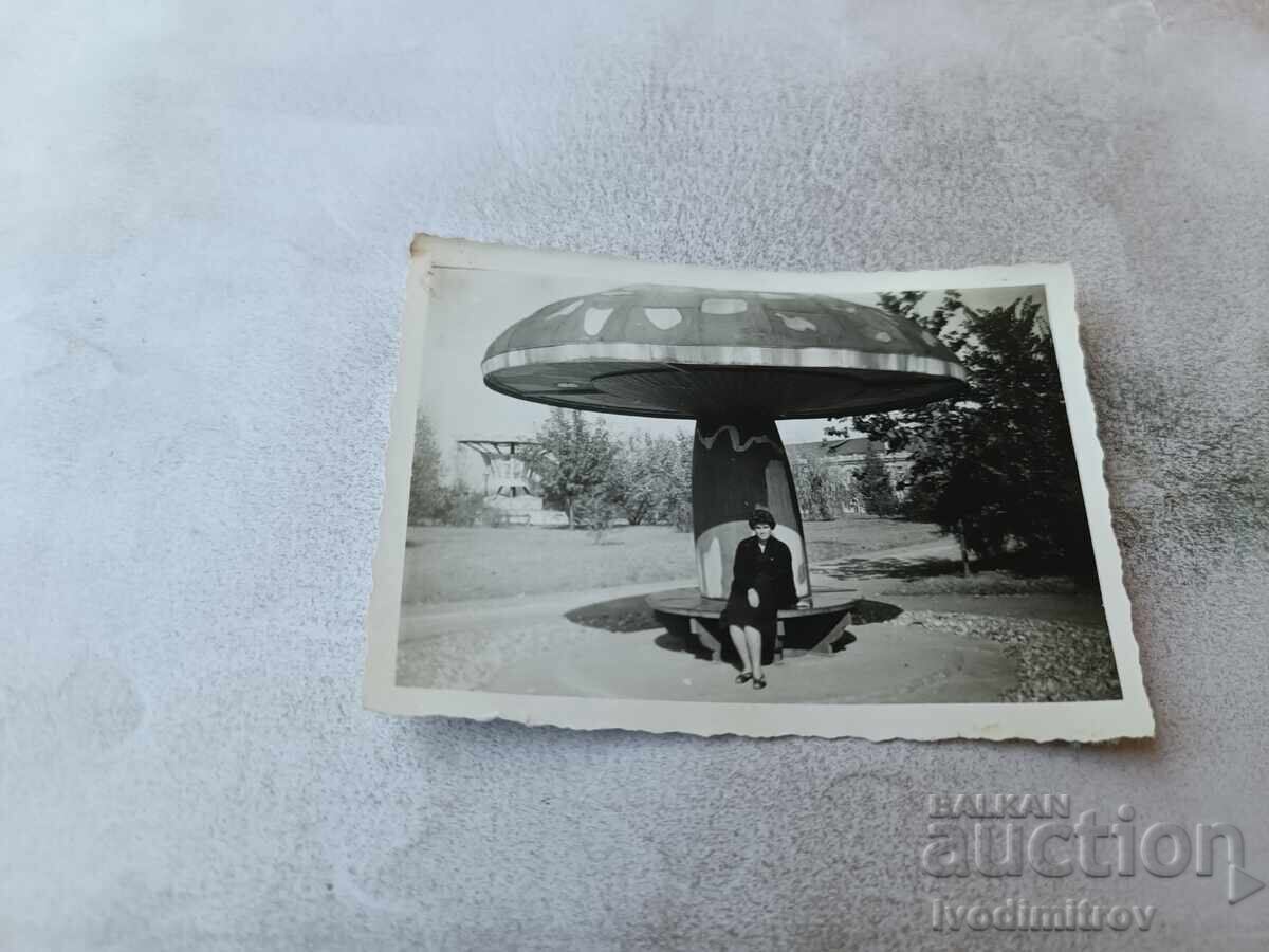 Fotografie Femeie așezată pe o bancă în formă de ciupercă în parc