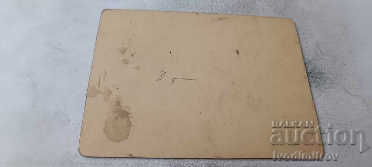 Fotografie Bărbat așezat pe un scaun în curtea unei case Carton cu preț € 4.46 | 8.72 BGN