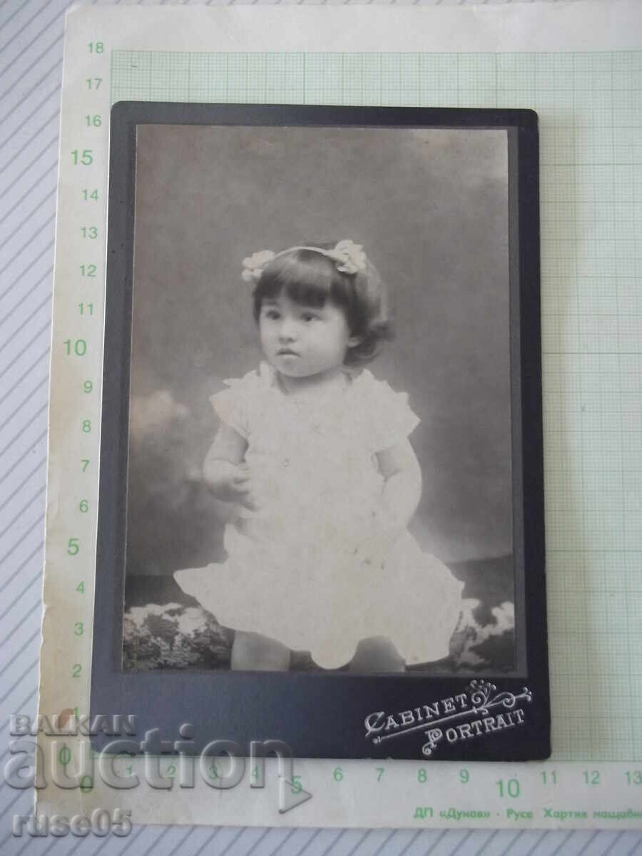 Fotografie veche pe carton cu un copil într-un studio foto
