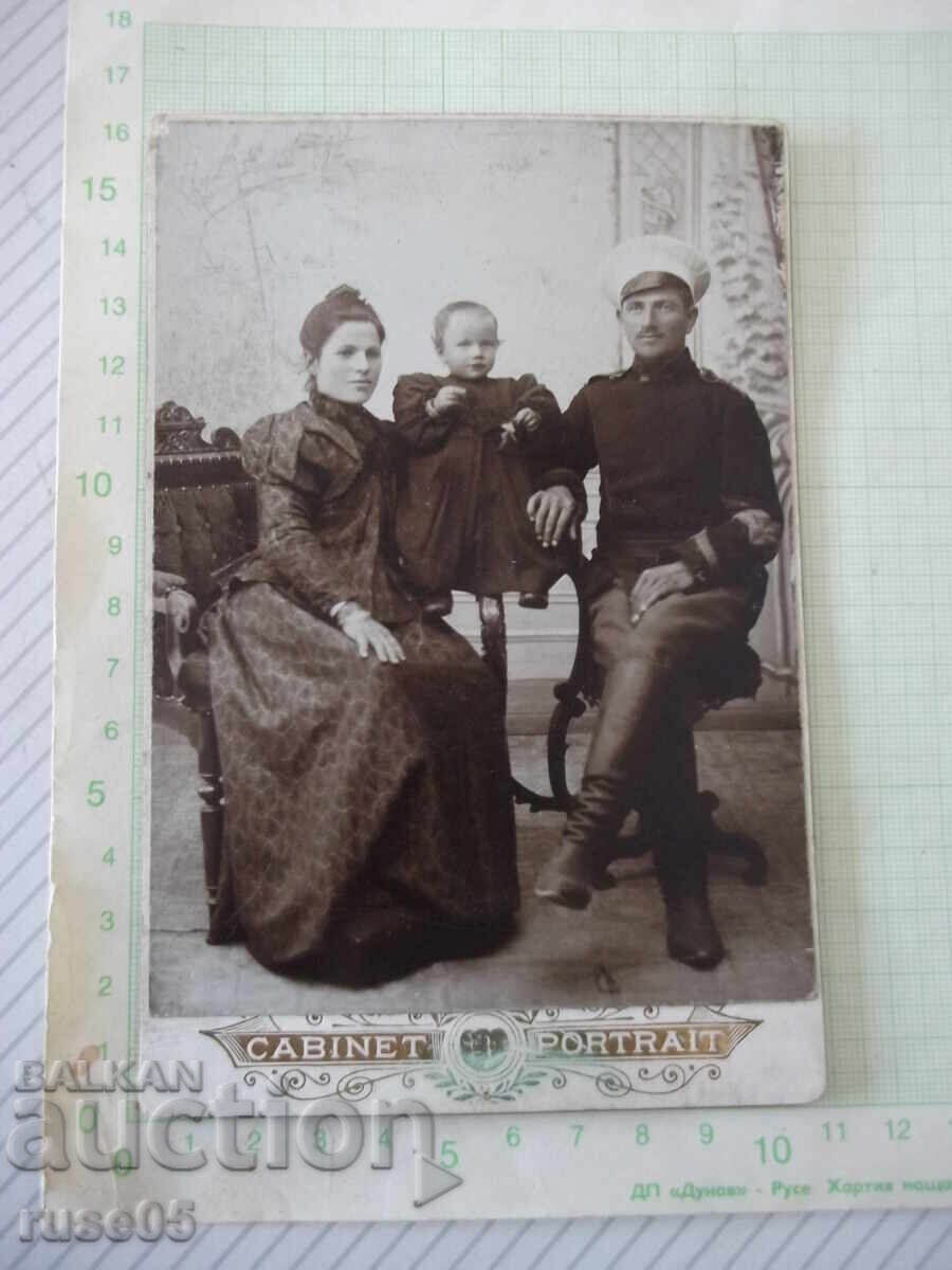 Fotografie veche pe carton cu un militar și familia sa într-un studio foto
