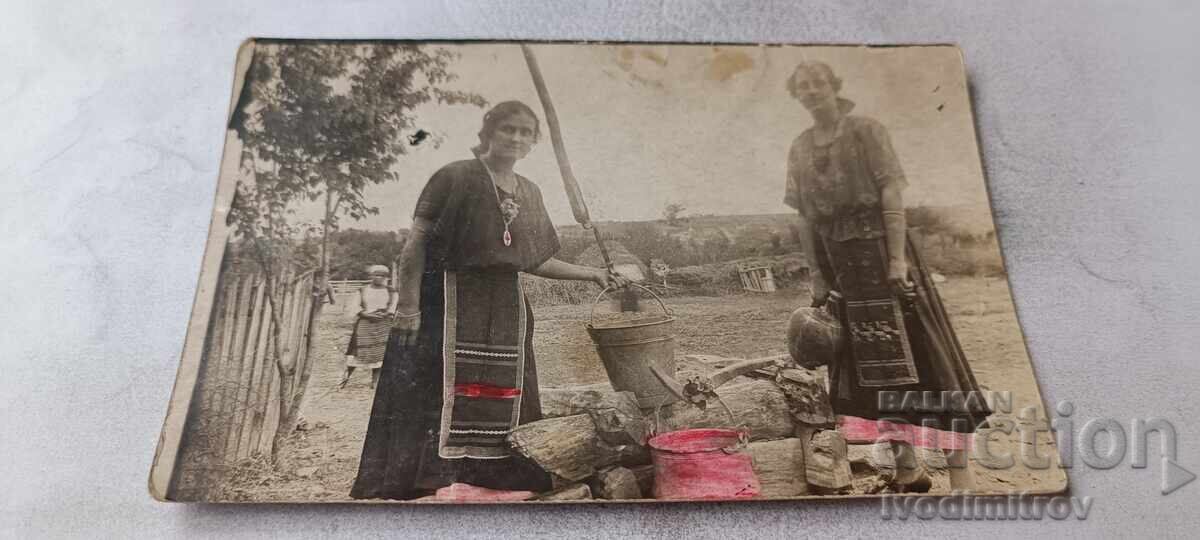 Fotografie Două femei care scot apă dintr-o fântână veche