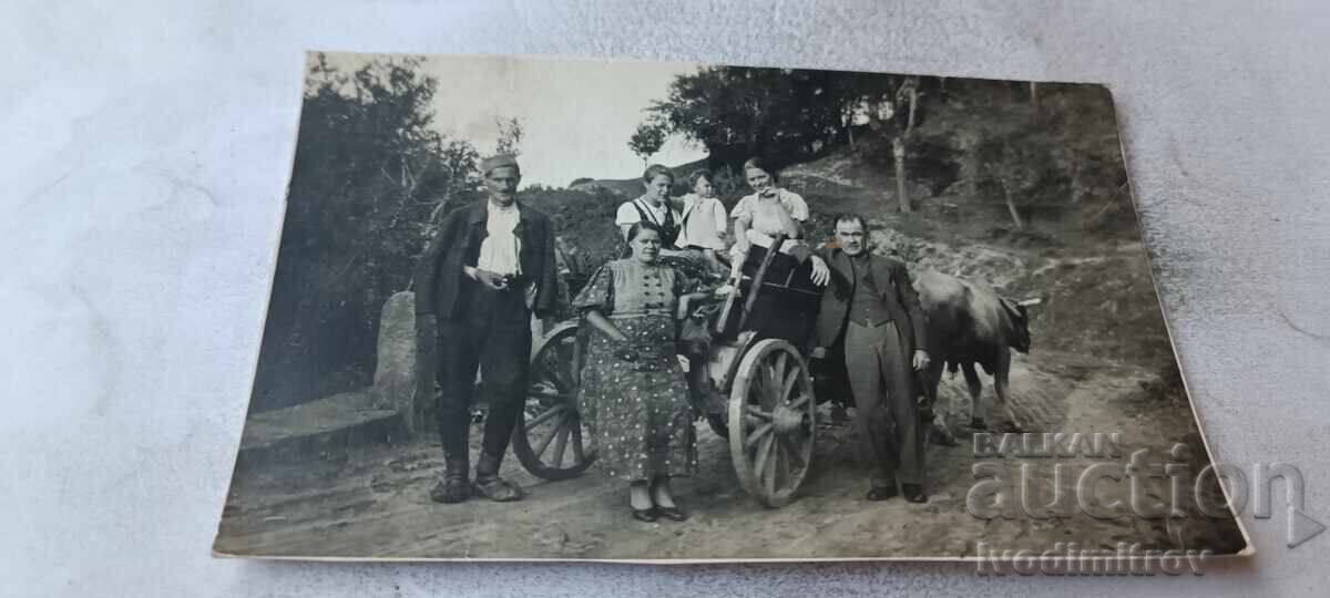 Photograph of men, women, and children with an ox cart on the road