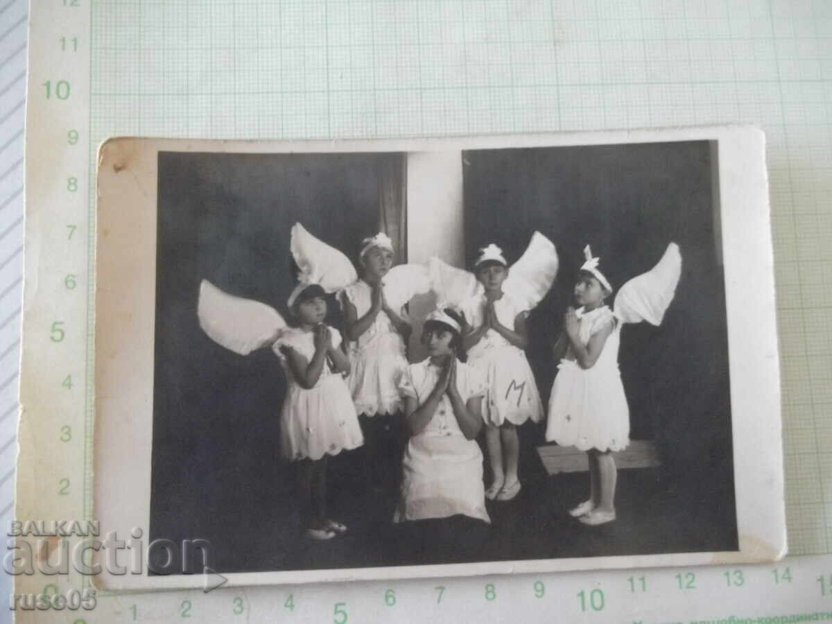 Fotografie veche cu un grup de copii îngerași într-un studio foto