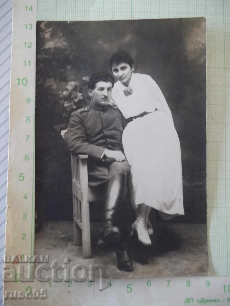 Fotografie veche cu un bărbat în uniformă și o femeie într-un studio foto