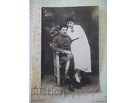 Fotografie veche cu un bărbat în uniformă și o femeie într-un studio foto