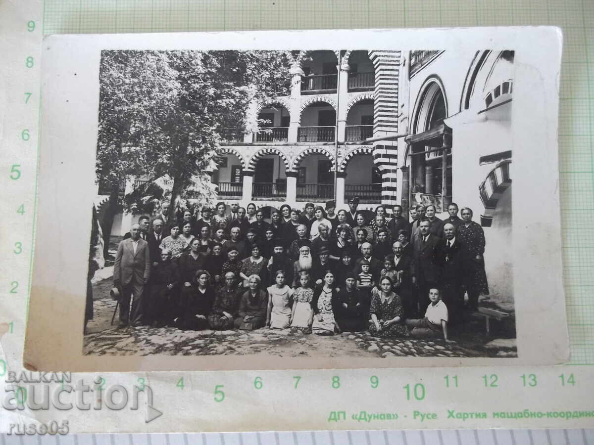 Fotografie veche cu un grup de credincioși într-o mănăstire cu preoți