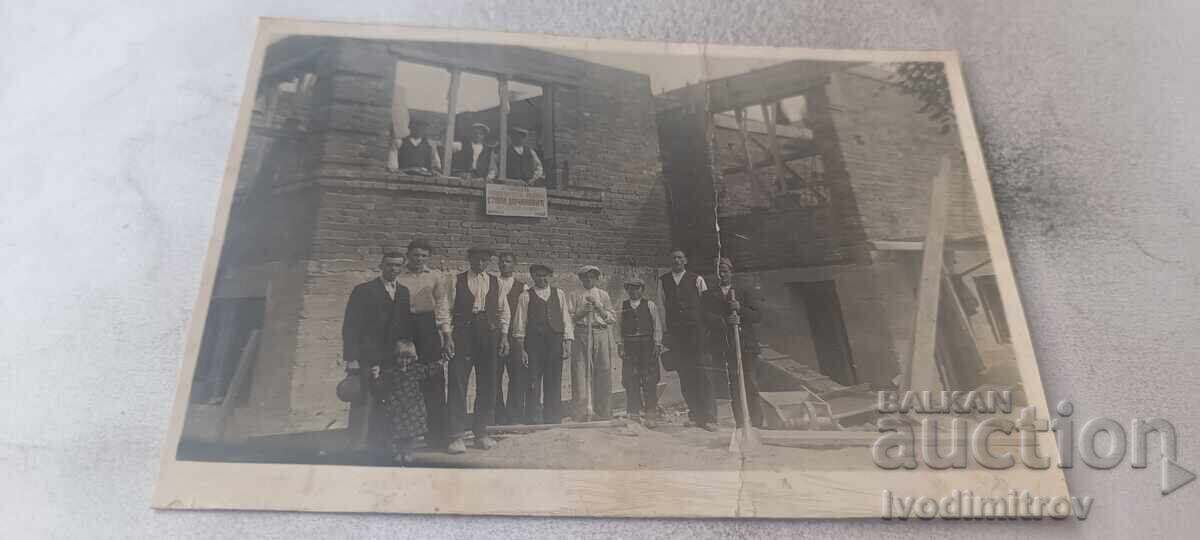 Photograph of men and boys in front of a house under construction Photograph of men and boys in front of a house under construction