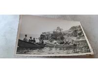 Photo of men, women, and a clergyman with boats on Lake Ohrid